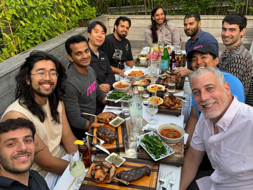 Several Rain team members pose for a photo while having dinner together at a restaurant